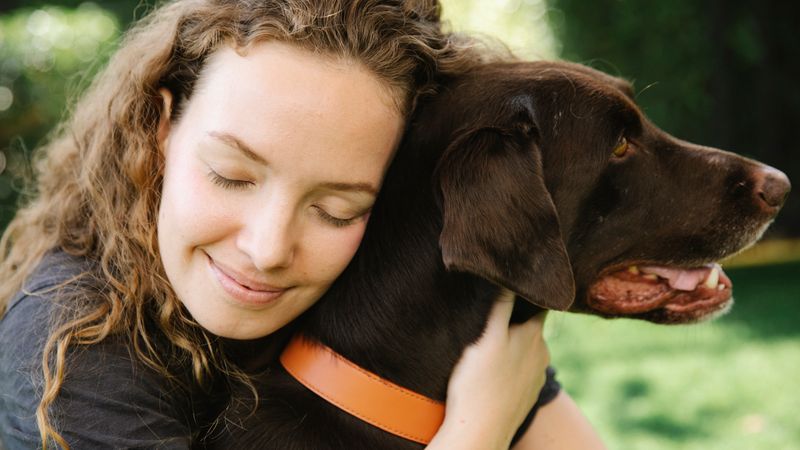 Femme câlinant tendrement son chien en extérieur - adopter un chien