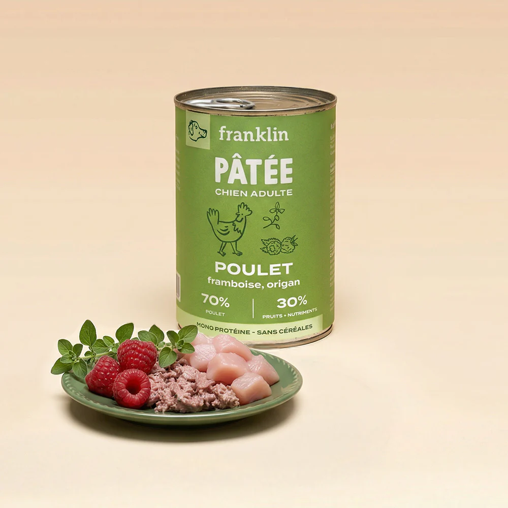 Boîte de pâtée Franklin poulet, framboise et origan, avec une assiette présentant la pâtée, des morceaux de poulet et des framboises