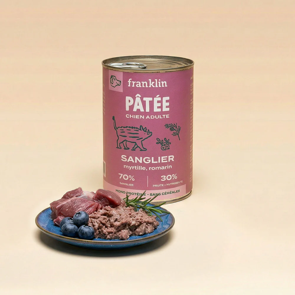 Boîte de pâtée Franklin sanglier, myrtille et romarin, avec une assiette montrant la texture de la pâtée, des morceaux de viande et des myrtilles