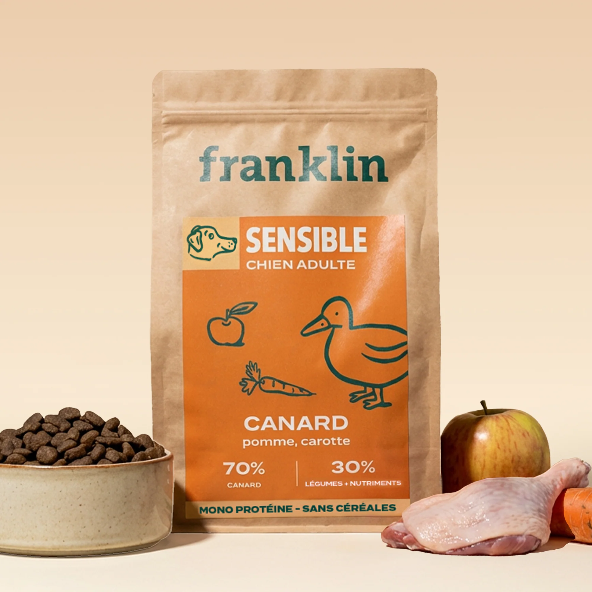Sachet de croquettes Franklin Sensible au canard, pomme et carotte, avec une gamelle de croquettes, une pomme et une carotte
